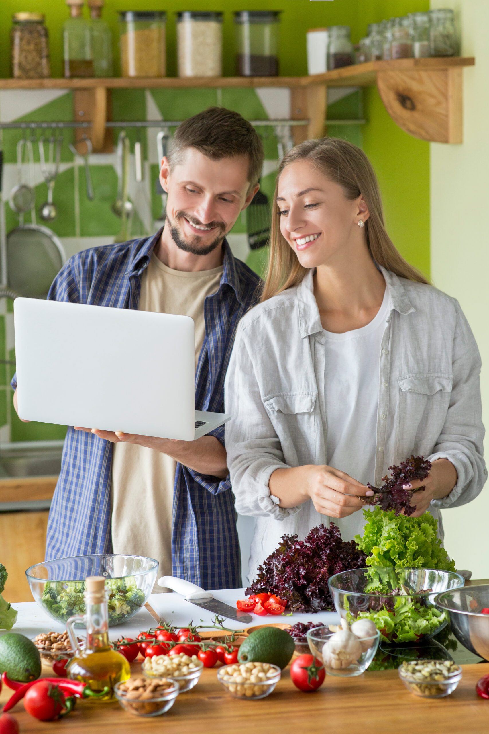 Coolinary online school. Happy vegetarian couple studying to cook healthy vegetarian food with laptop